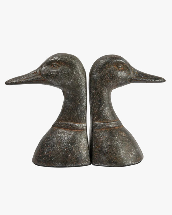 A pair of black cast metal duck head bookends on a white background.